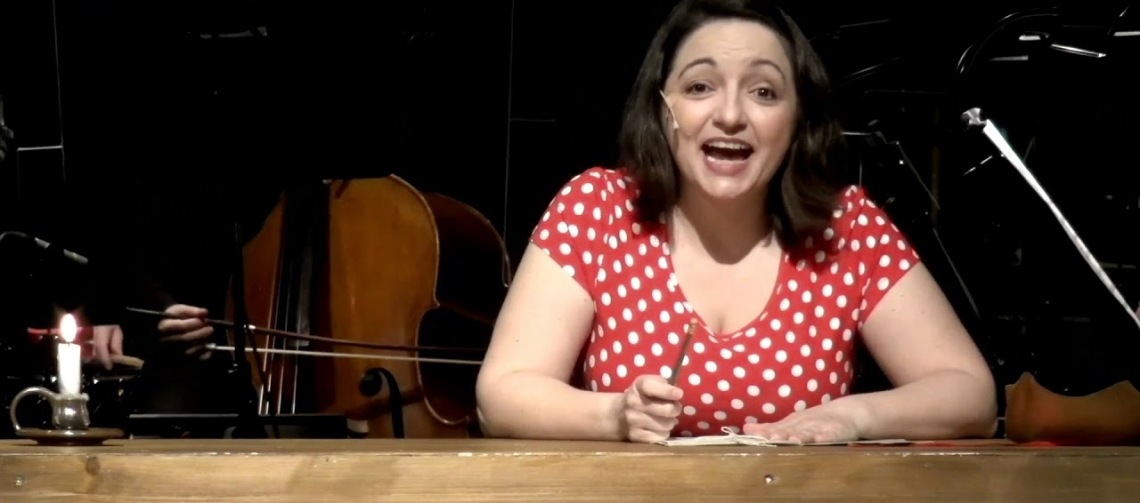 Miriam Sabba singing as Anne Frank on stage in front of an orchestra